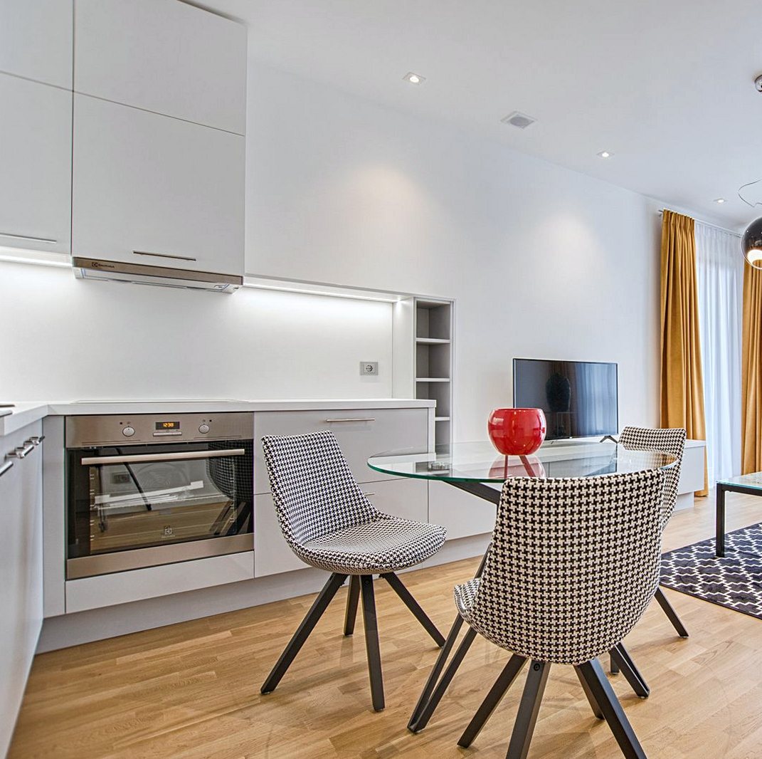 Fitted kitchen run with white units, a built-in oven and wood flooring